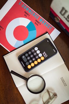 Overhead view of e-commerce chart with smartphone calculator and magnifying glass on a table.